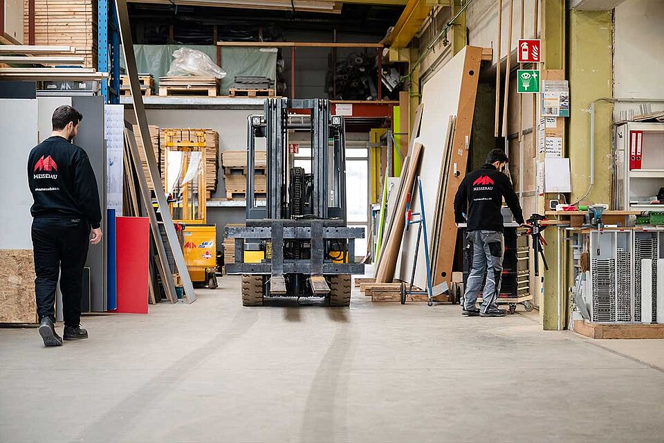 MA Messebau Eindruck Lager mit Gabelstapler und zwei Mitarbeitern