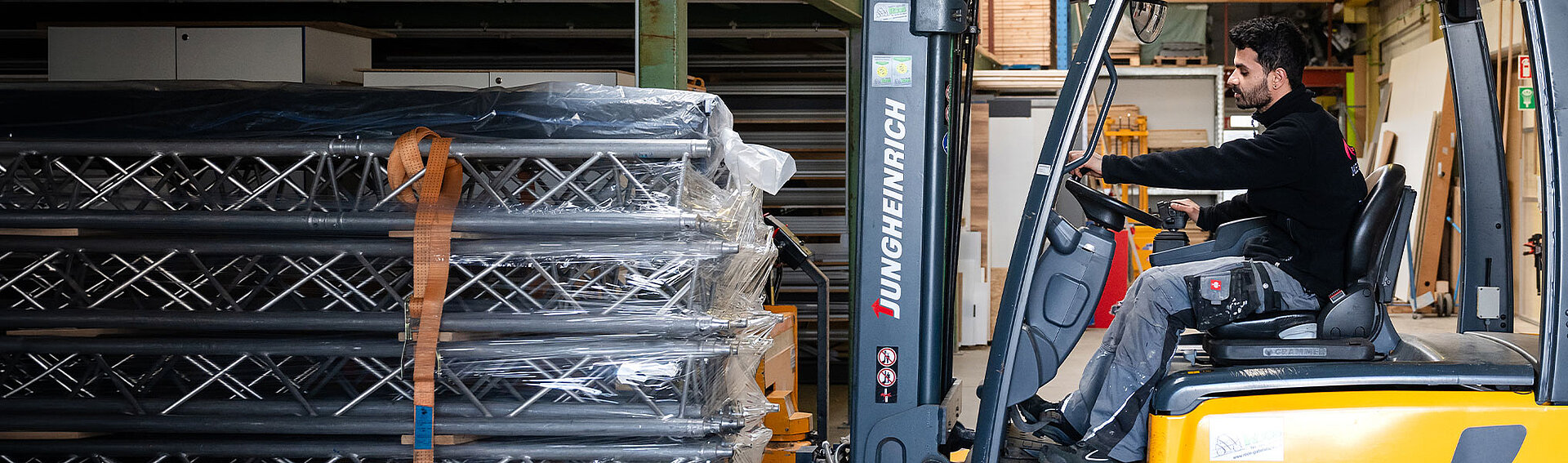 MA Messebau Lager Mitarbeiter holt Traversen mit Gapelstapler aus einem Regal