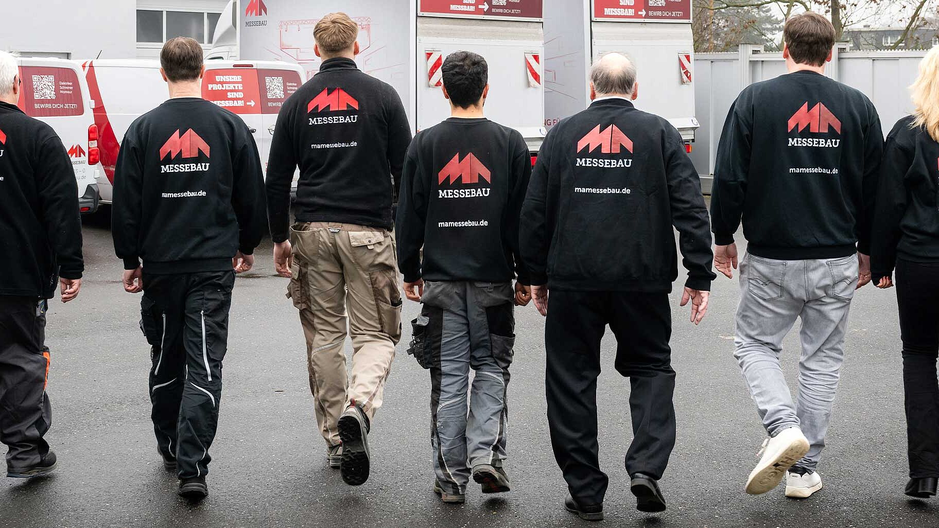 MA Messebau Header Unternehmen Mitarbeiter von hinten laufen auf Unternehmenssitz zu