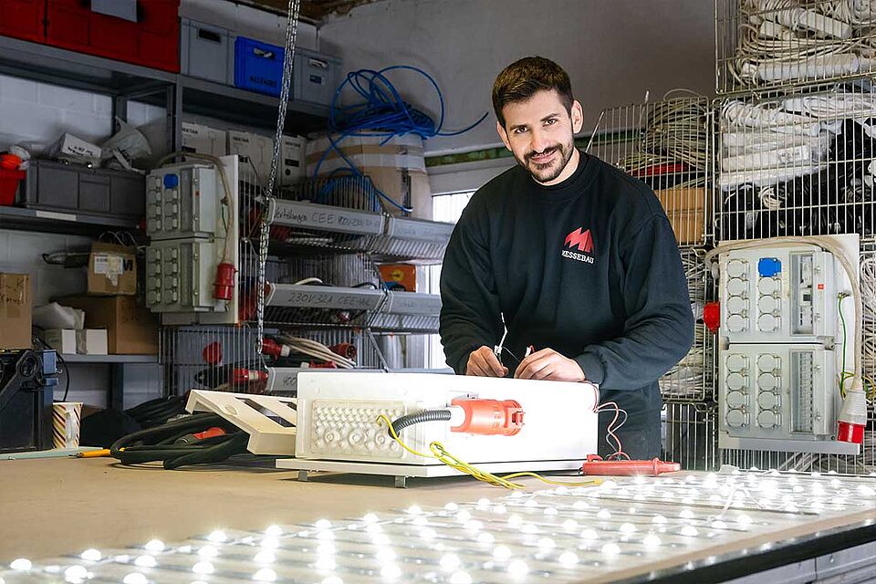 MA Messebau Mitarbeiter arbeitet an einem Schaltkasten